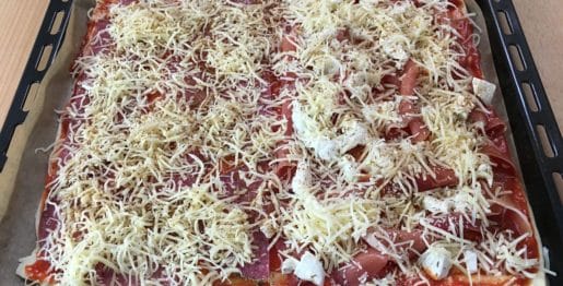 Selbstgemachte Pizza mit Salami, Schinken und Käse belegt
