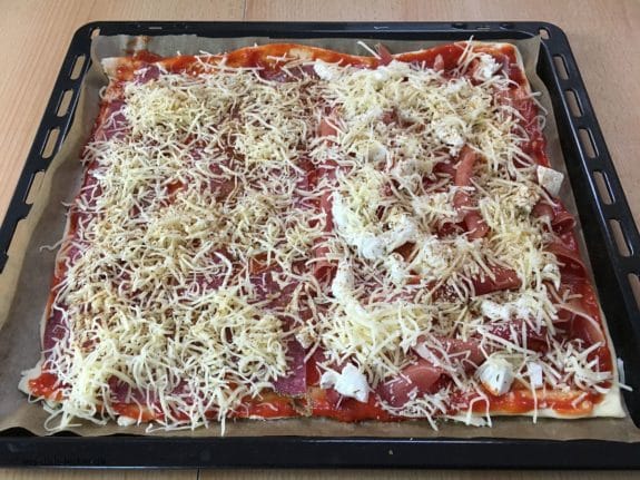 Selbstgemachte Pizza mit Salami, Schinken und Käse belegt