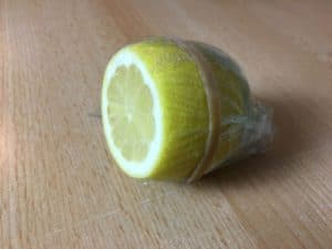 Plastik mit Gummi um eine Zitrone befestigt.