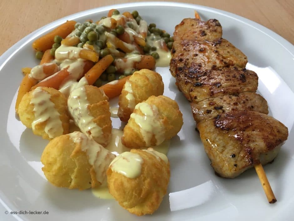 Schweinefiletspieße mit Kroketten, Erbsen und Möhren und Sauce ...