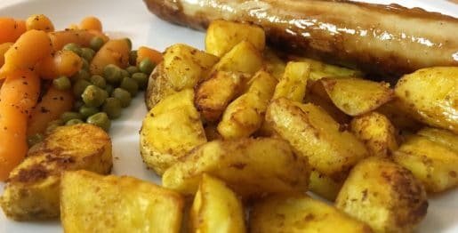 Geflügelbratwurst, Kartoffelspalten mit Erbsen und Möhren in Nahaufnahme