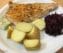 Putenschnitzel mit Pellkartoffeln und Rotkohl auf einem weissen Teller serviert